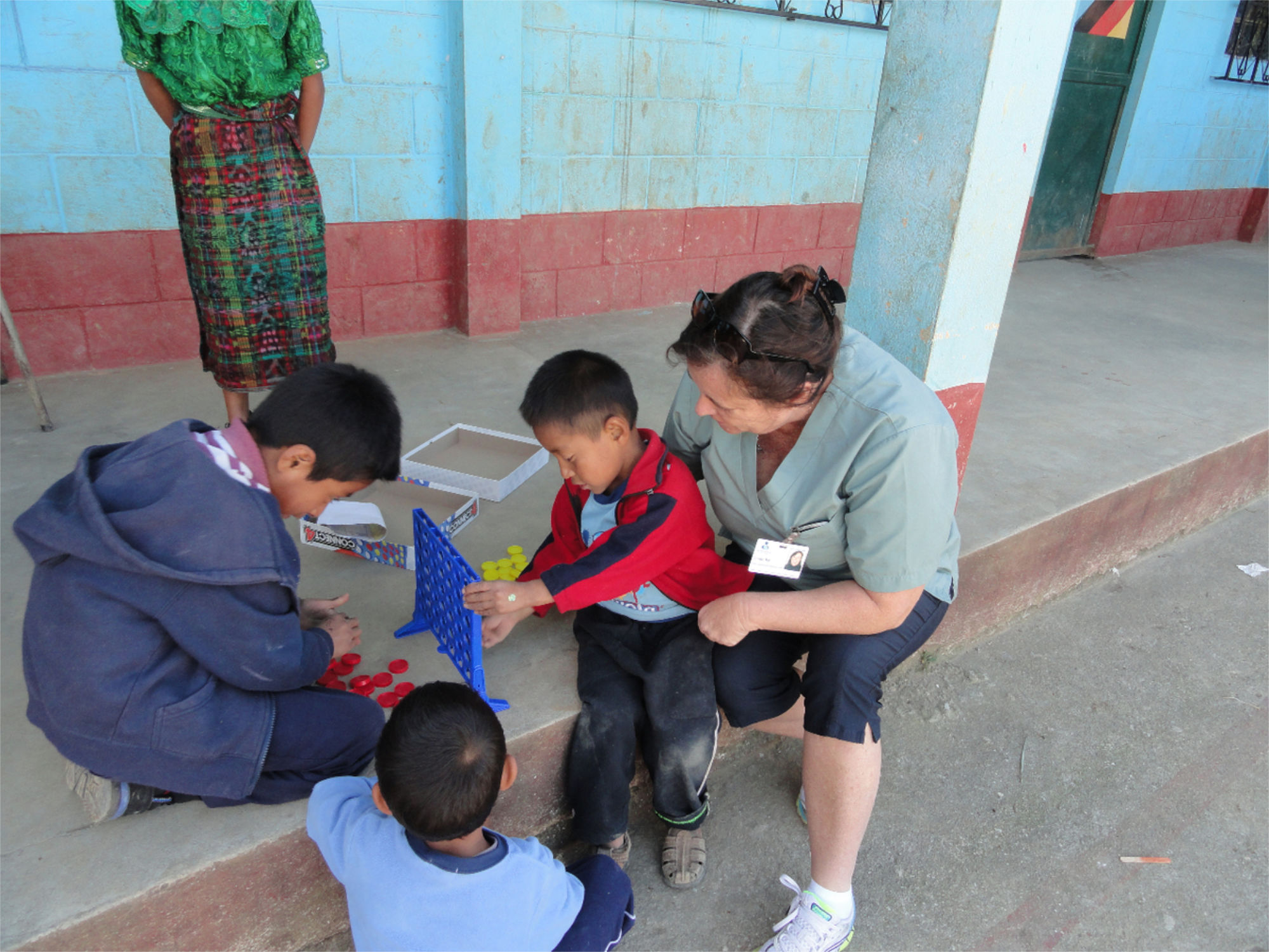 Kids playing connect 4 game with nurse outside